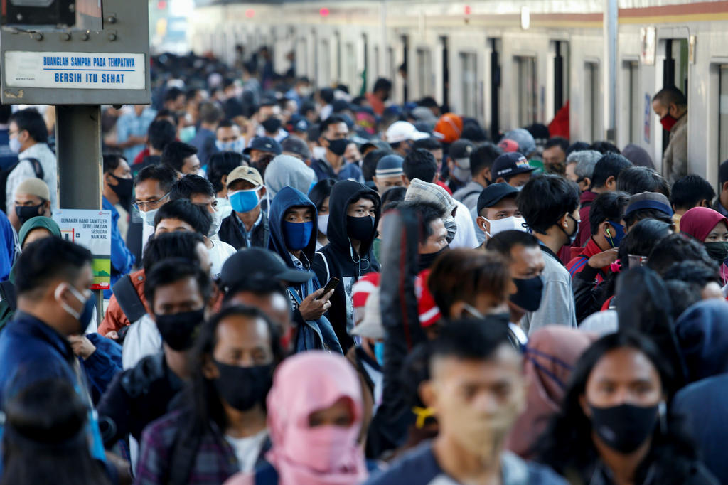 People wearing protective face masks amid the coronavirus disease (COVID-19) outbreak, make their way during rush hour at a train station in Jakarta,