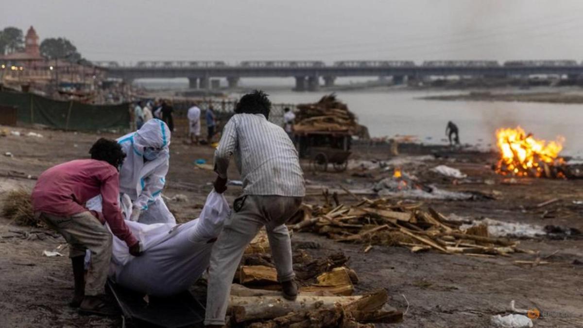 people-place-the-body-of-a-man-who-died-from-the-coronavirus-disease–covid-19—on-a-pyre-before-his-cremation-on-the-banks-of-the-river-ganges-at-garhmukteshwar-1