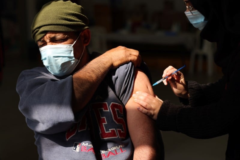 A Palestinian labourer who works within Israel or its settlements in the occupied West Bank, is vaccinated at an Israeli facility at Shaar Efraim crossing from Israel to the West Bank